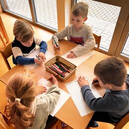 Kinder sitzen am Tisch und malen